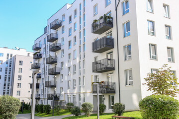 White modern apartment building with balconies and greenery