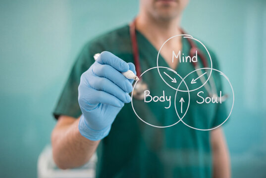 Doctor writing mind, body and soul diagram on glass for holistic healthcare and wellness concept.