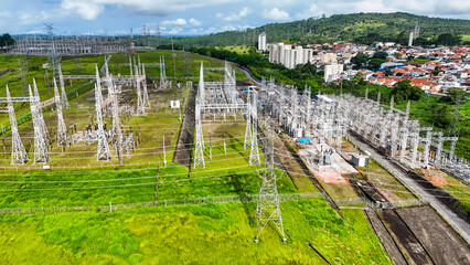 Visão aérea de torres de transmissão de energia elétrica em área urbana e rural, destacando a infraestrutura responsável pela distribuição de eletricidade. © rafaelnlins