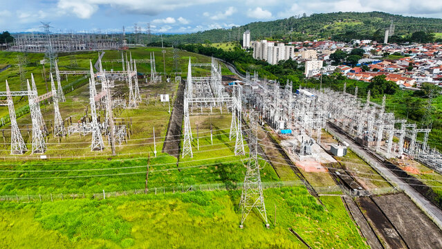 Vis&atilde;o a&eacute;rea de torres de transmiss&atilde;o de energia el&eacute;trica em &aacute;rea urbana e rural, destacando a infraestrutura respons&aacute;vel pela distribui&ccedil;&atilde;o de eletricidade.