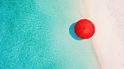 A bright red beach umbrella on pristine white sand by clear turquoise water, viewed from above.