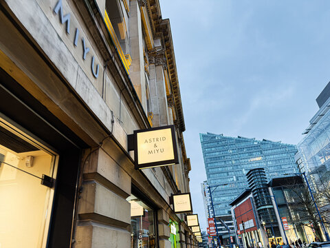 Urban shopping street in Manchester with storefronts and signage including Astrid Miyu boutique