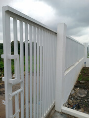 White metal fence and gate along rural roadside