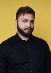 Fototapeta premium Man posing in front of yellow background while wearing a black shirt and showing a serious expression on his face