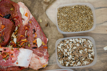Raw pieces of beef on the bone with garlic and a variety of spices in containers