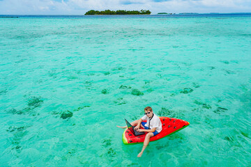 Fototapeta premium Young business boy. child in glasses works on a tropical island.