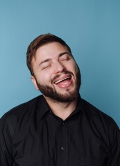 Obraz premium Man smiles widely with eyes closed against a blue background during indoor activity