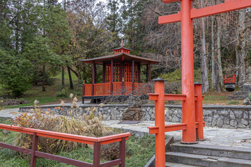 Japanese garden with wooden buildings. Japanese-style landscape design. A park with exotic trees. An oriental-style park area.