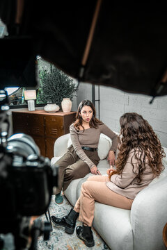 Two women discussing during a video interview, filmed by a camera in a professional indoor studio setting