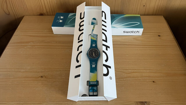 Livigno, Italy - February 3, 2026: Swatch wristwatch for Milano Cortina 2026 Olympic and Paralympic Games volunteers displayed in its original branded box on a wooden table