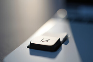 Close-up of silver metallic keyboard key with number 13, blurred background, for mockup or website