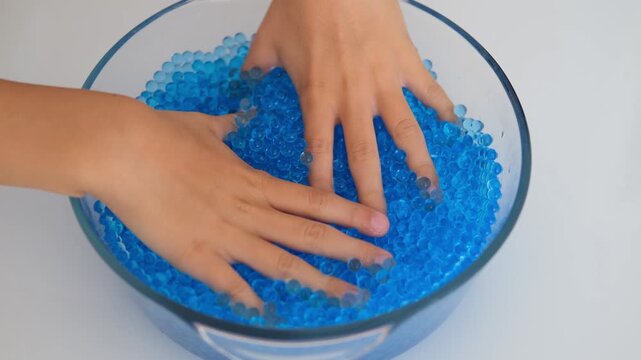Children's hands playing with blue Orbeez balls