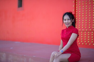 Joyful Woman in Red Dress Celebrating New Year Against Red Background