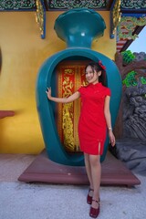 Young Woman in Red Dress Posing Near Decorative Vase in Celebration