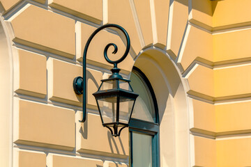 Timeless lantern casts soft shadow on ornate wall, evoking nostalgia and charm of old architecture. Warm sunlight enhances golden hues, creating sophisticated, serene atmosphere.