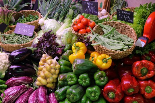 Aubergines (eggplant), bellpeppers and beans at green grocer's stand at local market hall Mercat Central in Alicante, Spain. Spanish food.