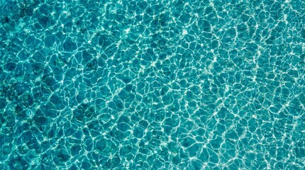 Obraz premium Aerial view of clear turquoise ocean water with shimmering sunlight reflections and ripple patterns, abstract water surface texture
