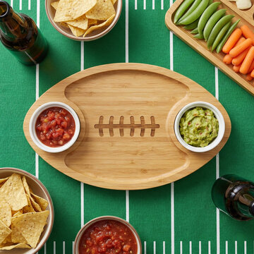 Game day snack board on football field table, guacamole salsa chips and veggies flat lay