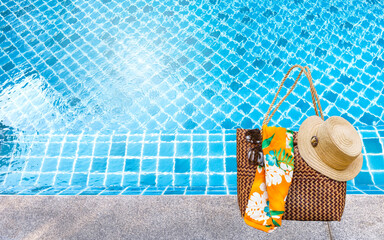 Summer season concept background, beach bag with hat and sunglasses on swimming pool edge, summer holiday begin