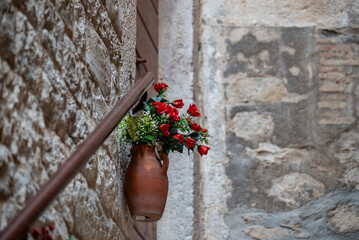 Terracotta vase with red roses on stone wall