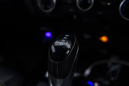 Modern Automatic Gear Shifter in Luxury Car Interior,Close-up shot of a modern automatic transmission gear stick in a car cockpit, featuring the P, R, N, D, and manual mode symbols. The dark, sleek.