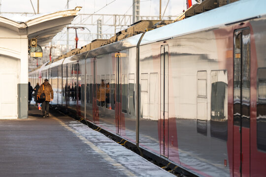 Modern city railway station with high-speed electrical train waiting on platform for departure while boarding passengers on a suburban rapid train. Hi-tech innovative public transportation for people.