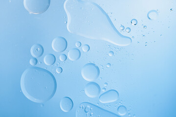 Water drops and oil bubbles forming an abstract texture on light blue background