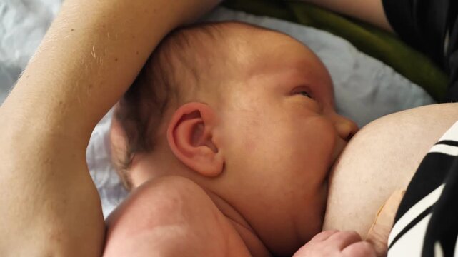 A tender close-up week-old infant nursing. The baby is nestled in its mother's embrace, highlighting the intimate bond of breastfeeding. Soft, natural light illuminates their skin