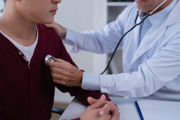 Doctor checking a young man's chest with a stethoscope, performing a health examination and...