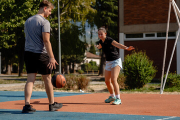 Basketball practice session in an outdoor court with two young players engaged in a drill in warm weather