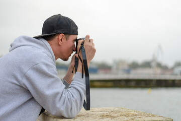 man wearing a gray hoodie is taking a picture with a digital camera