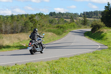biker on a custom classic motorcycle rides down the road, road traffic