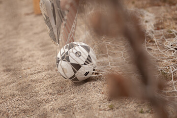 Fototapeta premium A soccer ball is tangled in a beach net on a sandy shore, capturing a dramatic close-up of outdoor sport and summer play with driftwood and netting in the background