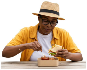 Woman in hat eating sandwich outdoors with condiment