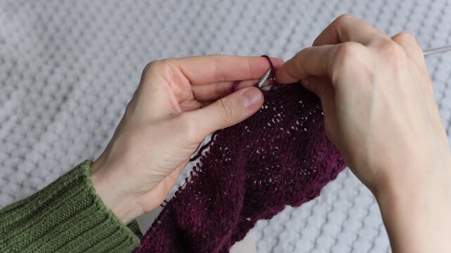 woman knits wool clothes on knitting needles. skills of making clothes from yarn, hobbies meditation. woman knits soft purple sweater at home. mental health, develop fine motor skills hands. handmade.