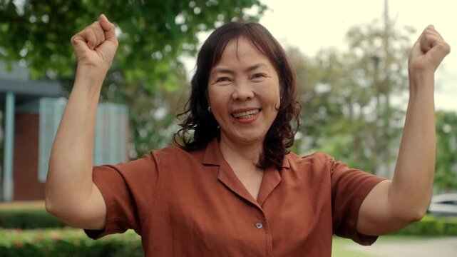 Portrait of smiling pretty senior asian woman 60 years old with urban natural park background, happy retirement lady with healthy aging in life security protection insurance for future planning.
