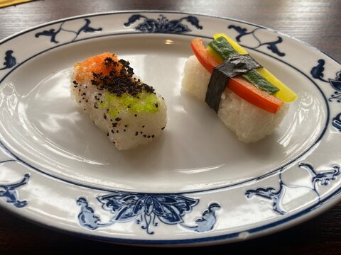 Echtfoto von Sushi Nigiri auf dekorativem Porzellanteller. Japanische K&uuml;che, minimalistische Pr&auml;sentation, frische Zutaten, authentische Foodfotografie, Restaurant, Genuss, Detailaufnahme.