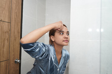Young Woman Applying Liquid Serum or Drops to Her Forehead