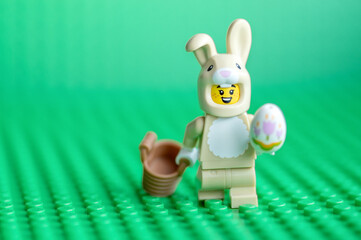 Naklejka premium Lego Easter Bunny with Egg and Basket on Green Baseplate. Easter holiday concept.