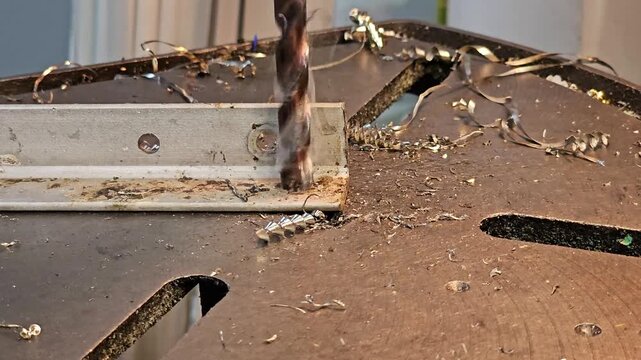Drilling a hole in a steel profile. Hot chips flying off the drill bit. Safety and hygiene in the locksmith's workplace.
