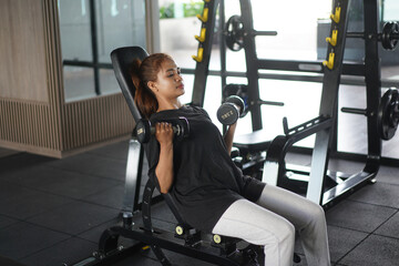 Focused woman performing seated incline dumbbell curls