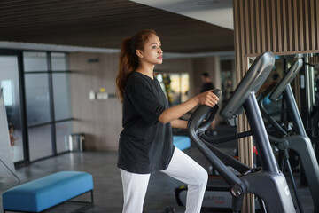 Fit woman exercising on elliptical cross trainer machine