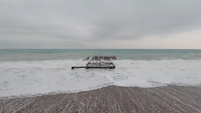 Ocean waves crashing into abandoned pier