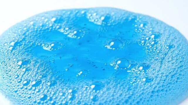 Close-up of a vibrant blue bubbly texture with numerous tiny air pockets on a smooth surface, creating an interesting abstract pattern