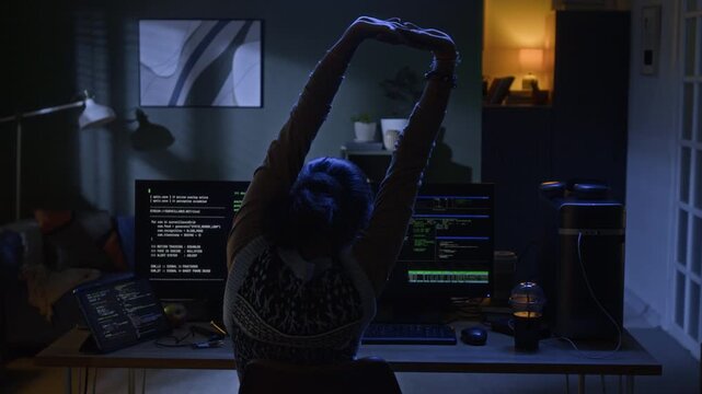 Interior shot of low key lit living room with cozy couch and home office desk standing in room decorated with framed wall pictures and green plants