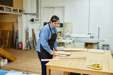 Focused young woman skillfully shapes wood at the workshop, surrounded by tools and inspiration.
