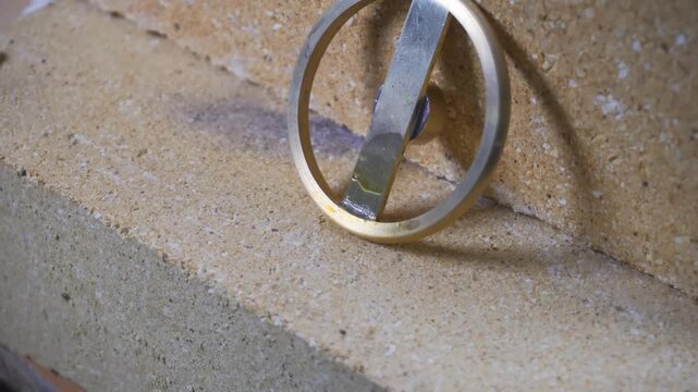 A complex brass pipe framework is secured on a firebrick surface while a technician uses a blowtorch and filler rod to apply intense heat to the metal joints for a permanent thermal bond