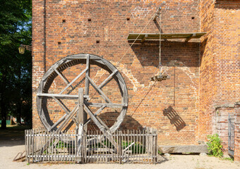 Obraz premium Medieval Wooden Treadwheel Crane at Rehna Abbey Germany Featuring Historic Red Brick Gothic Monastic Architecture and Traditional Construction Methods