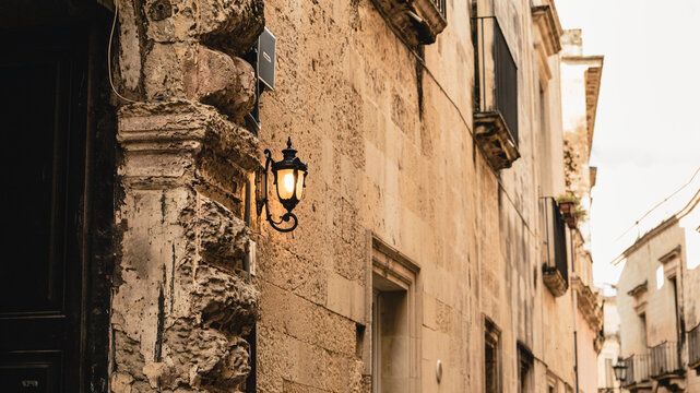 Old town in Italy, a shining lantern by an old wooden door,  characteristic sandstone buildings in Lecce