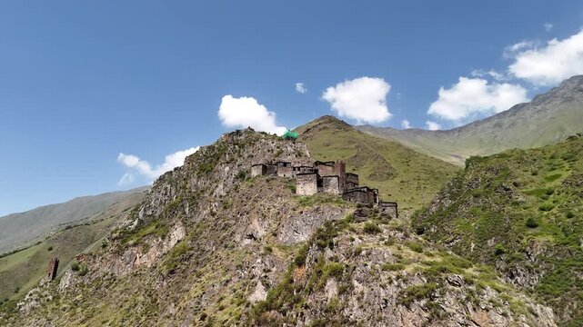 Aerial orbiting shot of the abandoned medieval village of mutso with its ancient stone towers perched on a rocky mountain slope in the caucasus of georgia